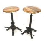 A pair of adjustable stools with a cast metal base. With wooden circular seats.