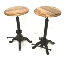 A pair of adjustable stools with a cast metal base. With wooden circular seats.