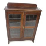 A vintage oak glazed display cabinet. With two leaded glass doors.