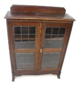 A vintage oak glazed display cabinet. With two leaded glass doors.