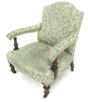 A low open upholstered armchair. Hump back, on turned tapering supports with casters.