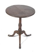 An 18th century oak circular tilt top tripod table with turned gun barrel, pedestal.