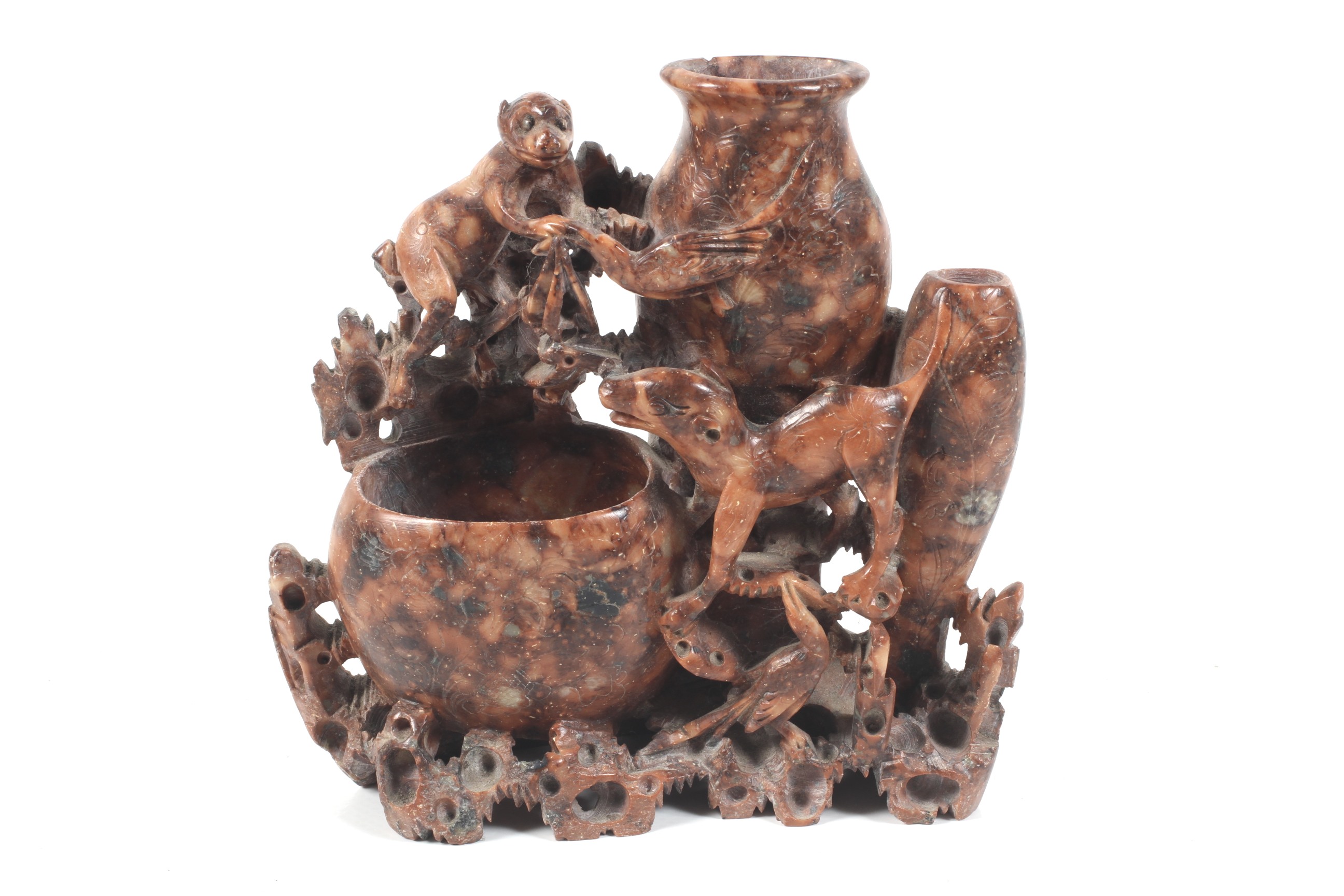 A Chinese carved soapstone carving. Depicting a monkey, dog and a bird standing by three open vases.