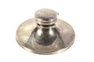 A silver round capstan shaped inkwell.