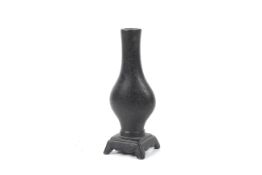 A Chinese Qing dynasty or earlier miniature bronze vase on an integrated base.