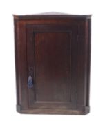 A George III oak panelled hanging corner cupboard containing three shelves. With key. H99cm x W74.