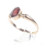 An early 20th century 9ct rose gold and small oval garnet single stone ring.