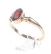 An early 20th century 9ct rose gold and small oval garnet single stone ring.