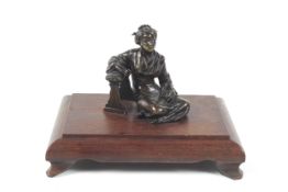 A 19th century Japanese patented bronze of a seated geisha leaning on an upholstered stool.