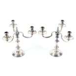 A pair of silver round candlesticks with three light candelabra.