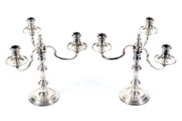 A pair of silver round candlesticks with three light candelabra.