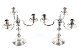 A pair of silver round candlesticks with three light candelabra.