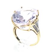 A modern 9ct gold, kunzite and diamond dress ring. Centred with an oval mixed-cut kunzite, approx.