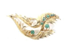 A vintage emerald abstract scrolling leaf brooch.