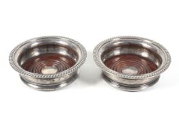 A near pair of vintage silver round bottle coasters.