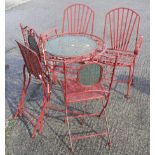 A set of metal garden furniture painted red.