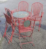 A set of metal garden furniture painted red.
