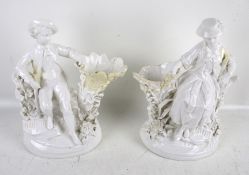 A pair of white glazed vases after Meissen. Modelled as a man and woman beside a tree trunk, H20.