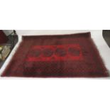 An Afghan red wool rug. With geometric boarder and central decoration.