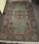 A Persian style wool rug. With light green ground and decorative border.