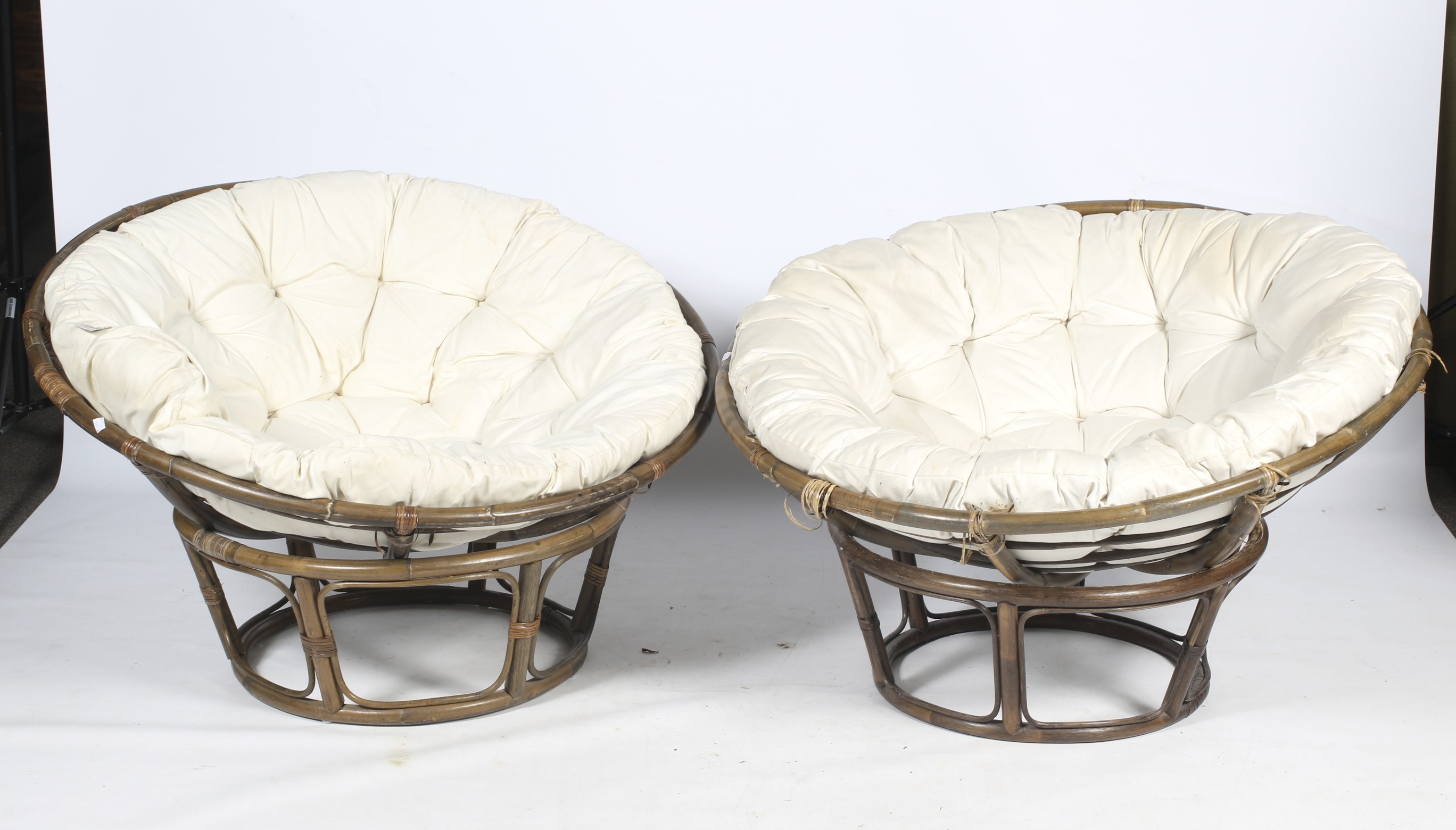A pair of bamboo 'basket' lounge chairs with cushion.