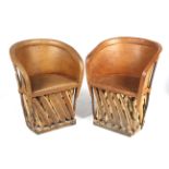 A pair of wood and tan leather tub chairs.