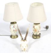 A pair of table lamps and a deer skull with antlers.