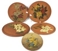 Five Torquay terracotta wall plaques. Including a Watcombe example, all painted with flowers.