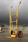 A set of yellow painted metal sack trucks.