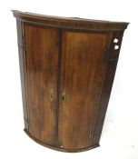 A George III mahogany cross banded bowfront corner cupboard.