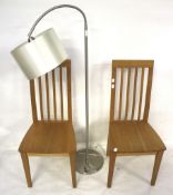 A pair of contemporary wooden chairs and a brushed steel standard lamp.