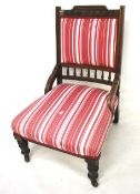 An Edwardian upholstered wood framed chair. On turned supports and casters.