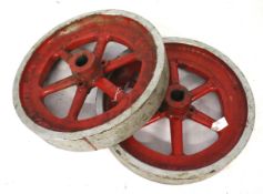 Two cast metal fly wheels painted red.