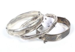 Three silver bangles including a slave bangle resembling bamboo.