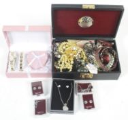 A collection of costume jewellery in a black box and some loose.