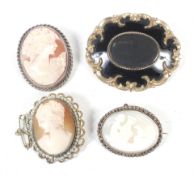 An early Victorian gold-plated and black enamelled shaped-oval mourning brooch and three oval shell