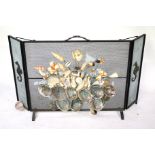 A mid-century wrought iron folding fire screen. Guard later decorated with mixed seashells.