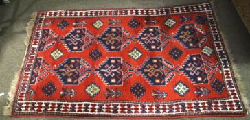 A Persian style red ground wool rug. With geometric border and decoration.