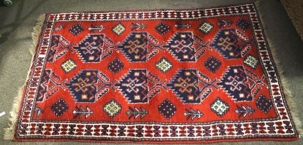 A Persian style red ground wool rug. With geometric border and decoration.