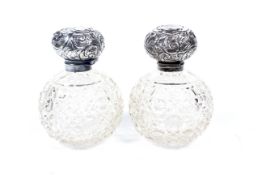 A pair of Edwardian silver mounted clear cut glass globular scent bottles.