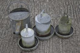 A galvanized metal watering can and three chicken feeders.