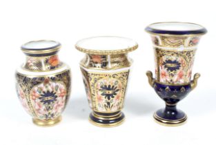 Three Royal Crown Derby miniature urns and a vase. Max. H7.