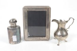 A silver cream jug, flask and photograph frame.