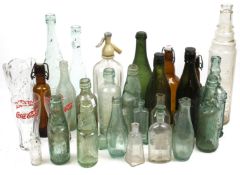 An assortment of vintage glass bottles. Including advertising glasses, a soda syphon, etc.