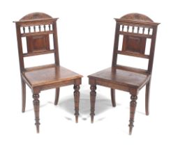 A pair of hall chairs. With a carved roundel to the top rail, solid seat and turned front legs. H91.
