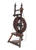 A 19th century stained wood spinning wheel with turned finials.
