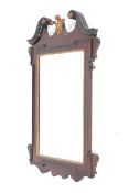 A reproduction mahogany framed neoclassical style wall mirror decorated with fleur-de-lis.