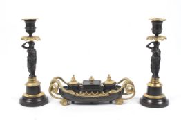 A 19th century Regency style patinated bronze and ormolu inkwell and pair of candlesticks.