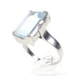 An aquamarine single stone ring. The pale blue rectangular step cut stone approx. 7.
