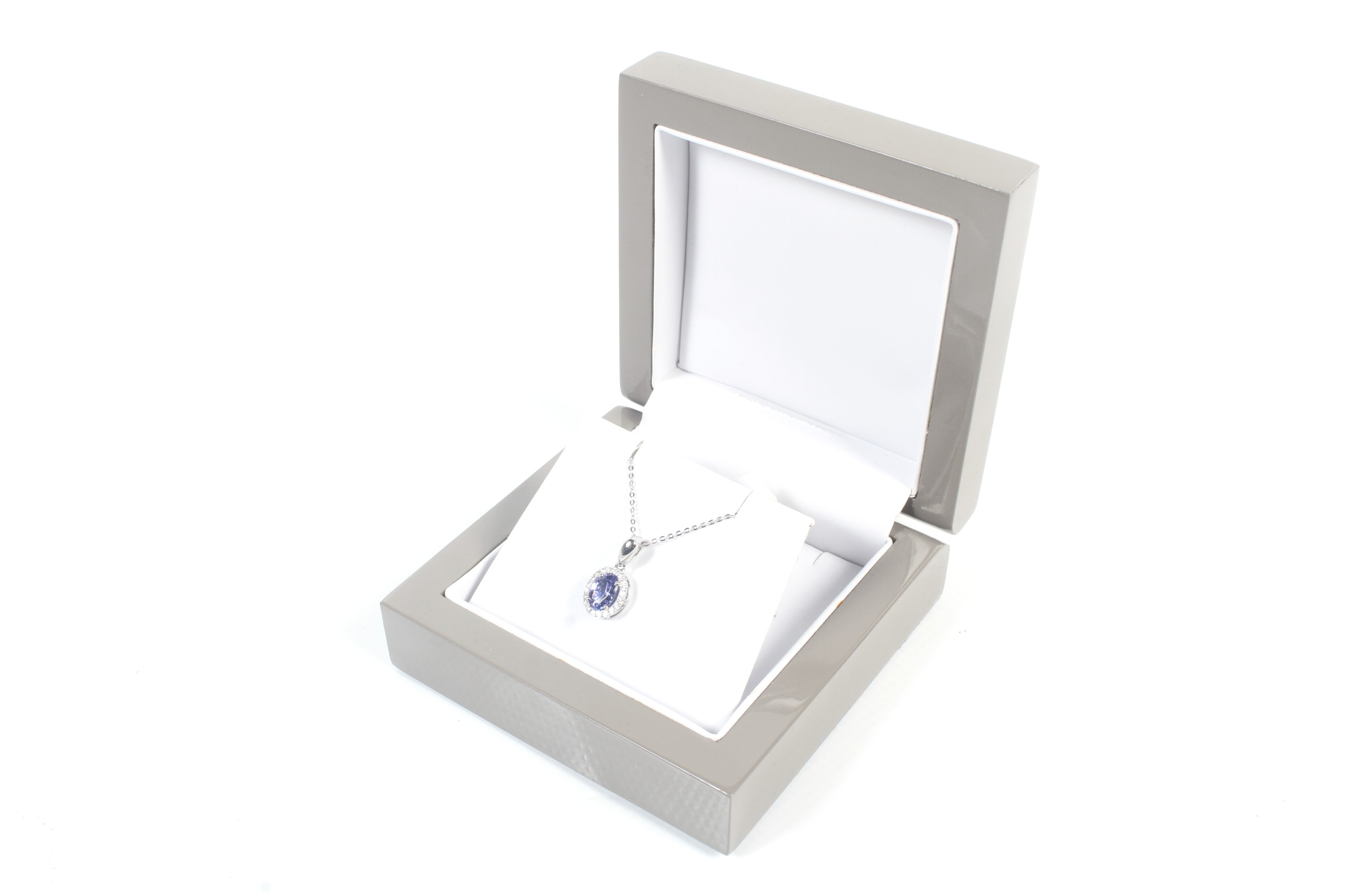 A modern platinum, tanzanite and diamond oval cluster pendant and chain.
